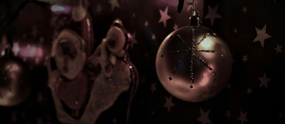 a close up of a christmas ornament on a wall, by Julia Pishtar, pexels contest winner, magical realism, dark and stars in the background, pink, cinema 4d cinematic, desaturated