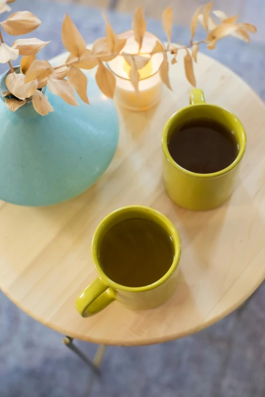 two cups of coffee sit on a table, by Jessie Algie, chartreuse color scheme, moringa juice, teals, peaceful