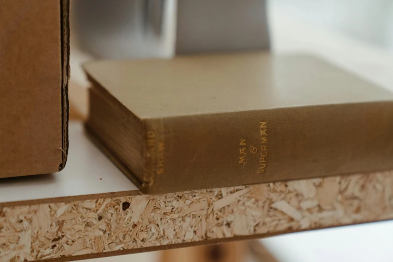 a stack of books sitting on top of a wooden table, unsplash, private press, gold detailed line work, close-up product photo, background image, etched inscriptions