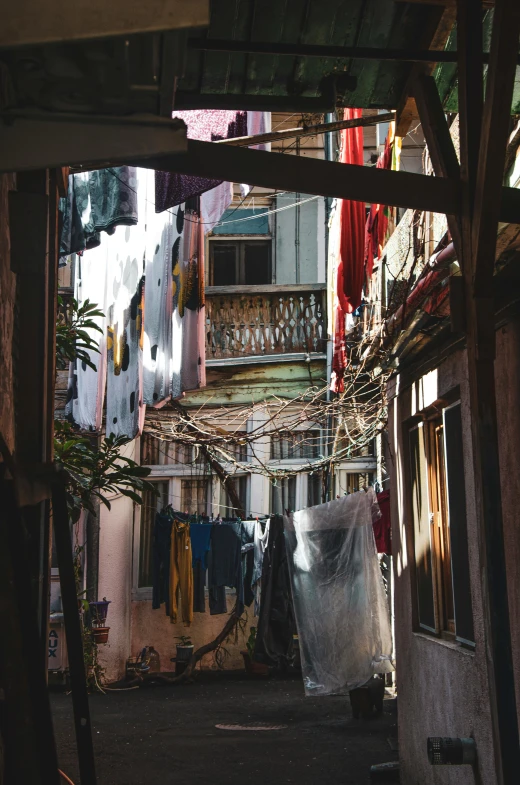 a narrow alley with clothes hanging out to dry, a silk screen, unsplash contest winner, poor quality, slums, vines hanging down, late afternoon light