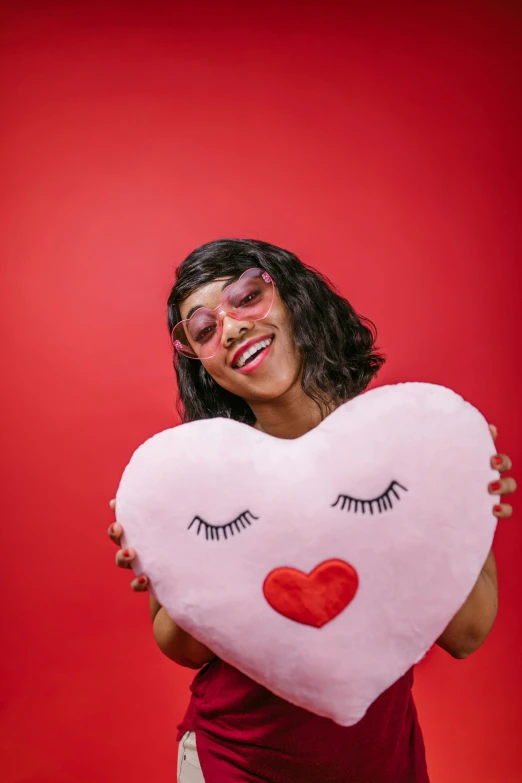 a woman holding a heart shaped pillow with eyelashes on it, trending on pexels, pop art, mixed race woman, fumo plush, inflatable, a handsome