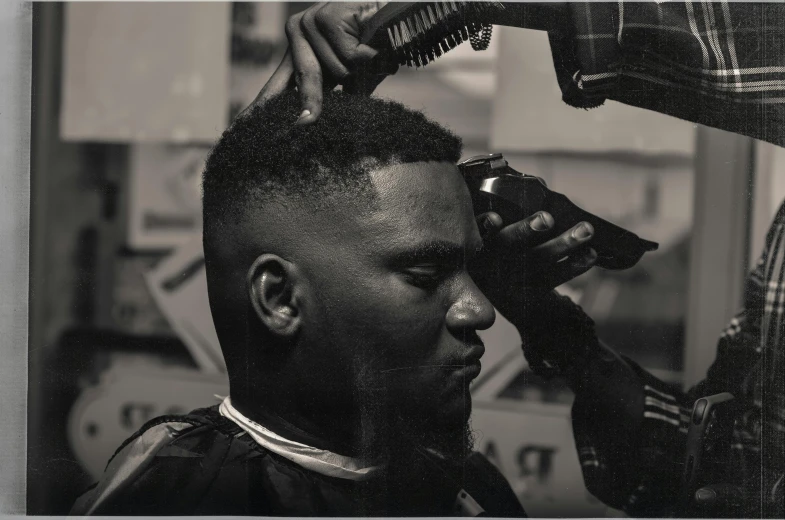 a black and white photo of a man getting his hair cut, inspired by Paul Georges, wakanda, professionally color graded, thumbnail, profile pic