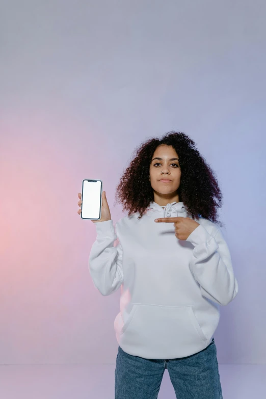 a woman taking a selfie with her phone, an album cover, pexels, mixed race, wearing a white sweater, pointing index finger, plain background