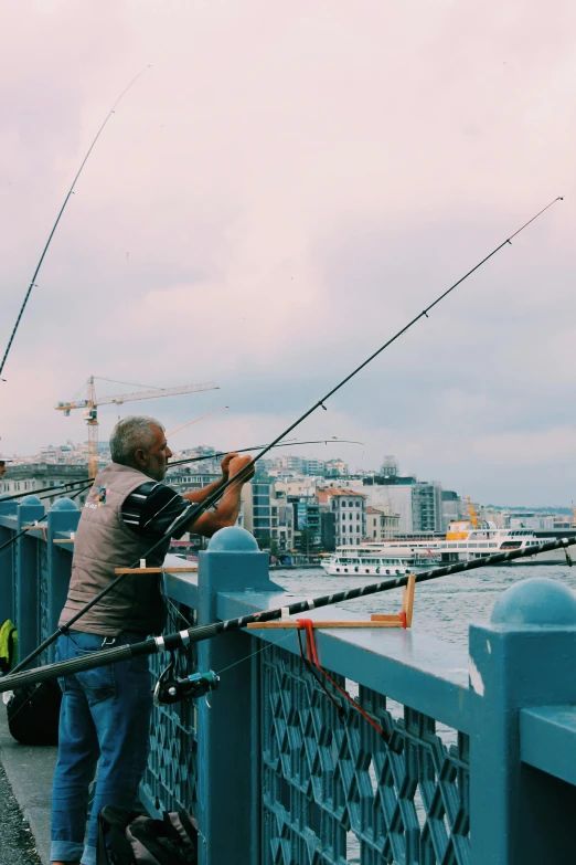 a man standing on top of a bridge next to a body of water, fishing pole, auckland sky tower, fish hooks, camaraderie