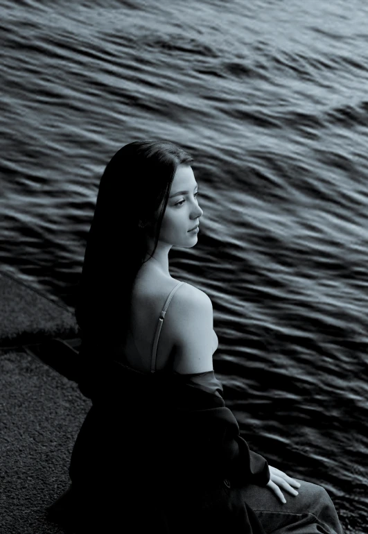 a woman sitting next to a body of water, a black and white photo, by irakli nadar, album cover, andrei markin, calm night. over shoulder shot, renato muccillo