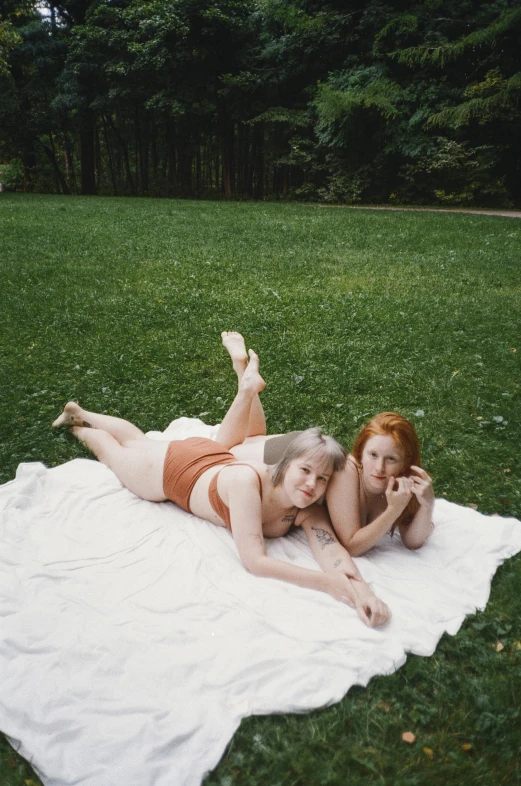 a couple of women laying on top of a white blanket, by Ren Hang, unsplash, realism, albino white pale skin, in a park, ( redhead, picnic