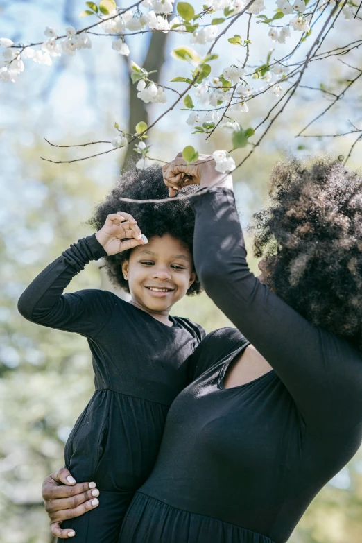 a woman holding a little girl in her arms, pexels contest winner, branches sprouting from her head, with afro, spring time, black main color