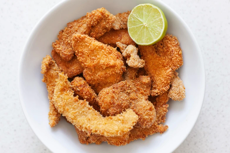 a white bowl filled with fried fish and a lime wedge, by Carey Morris, chicken nuggets, thumbnail, banana, longque chen