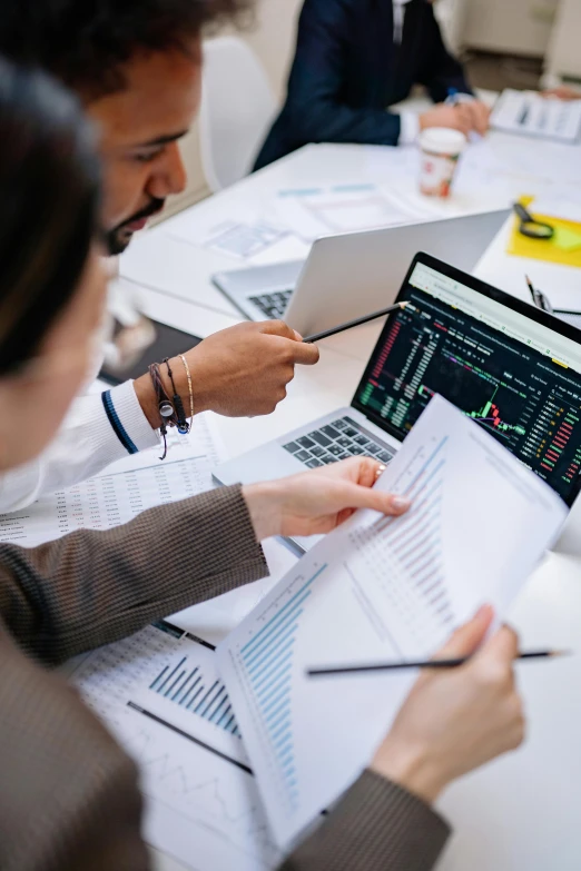 a group of people sitting around a table with laptops, trending on unsplash, analytical art, displaying stock charts, wētā fx, high quality photo, medium closeup