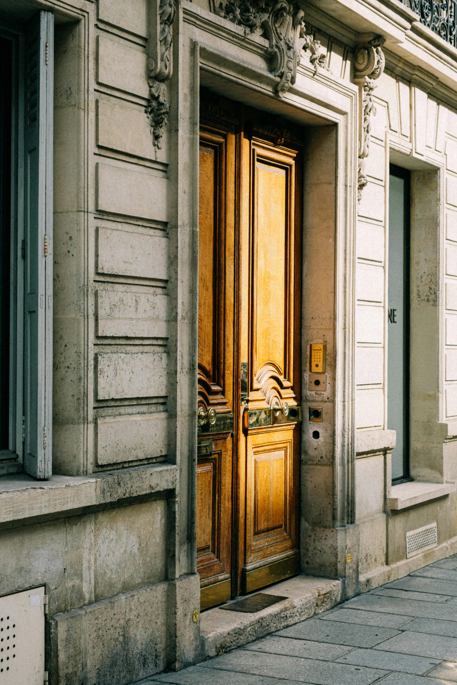 a person walking down a sidewalk in front of a building, by Sven Erixson, trending on unsplash, neoclassicism, wood door, gilded with gold, france, grain”
