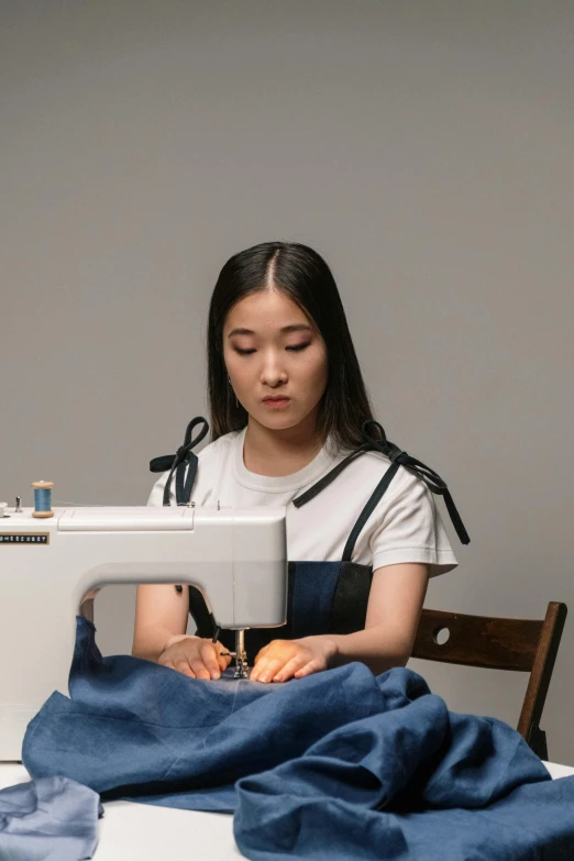 a woman sitting at a table working on a sewing machine, inspired by Kim Tschang Yeul, wearing a cute top, ignant, architect, promo image