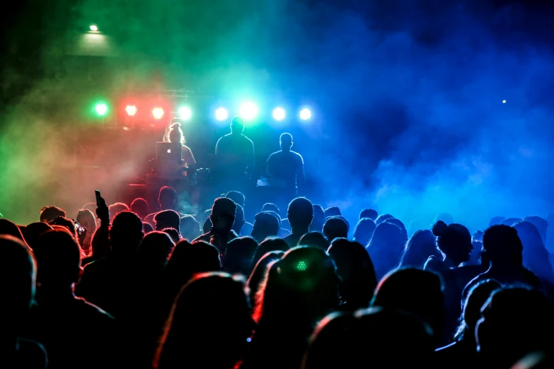 a group of people standing on top of a stage, by Joe Bowler, pexels, party lights, blue and green and red tones, music being played, coloured