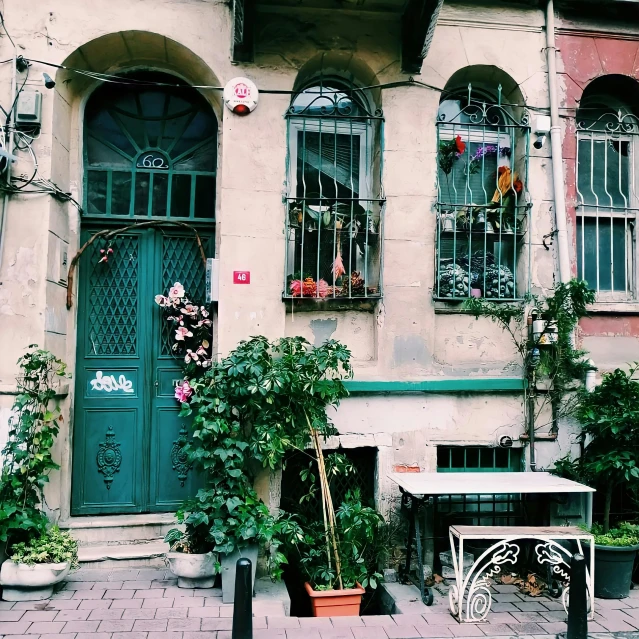 a couple of benches sitting in front of a building, by Niyazi Selimoglu, pexels contest winner, art nouveau, doors to various living quarters, turqouise, 1990's photo, wrapped in cables and flowers