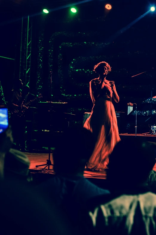 a woman standing on top of a stage holding a microphone, pexels, happening, jazz, dreamy night, enhanced, a wide shot