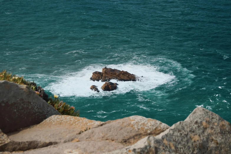 a large body of water next to a rocky shore, pexels contest winner, les nabis, nazare (portugal), random detail, offshore winds, high quality product image”