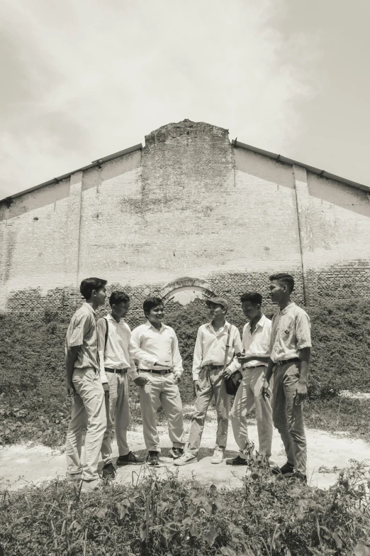a group of men standing in front of a building, pexels contest winner, bengal school of art, aged 13, panoramic shot, prison, 1990 photograph