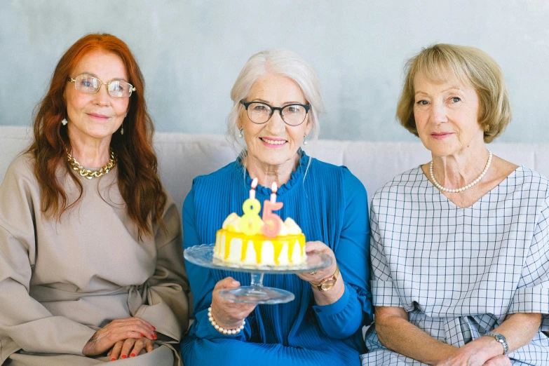 three women sitting on a couch holding a cake, pexels contest winner, elderly, standing elegantly, yellow, 15081959 21121991 01012000 4k