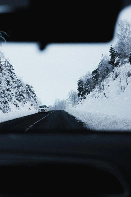 a car driving down a snow covered road, in the distance, inside of a car, from the distance, head shot