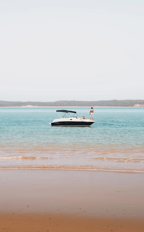 a man standing on top of a beach next to a boat, by Lee Loughridge, unsplash, minimalism, australian beach, female floating, 15081959 21121991 01012000 4k, 3 boat in river