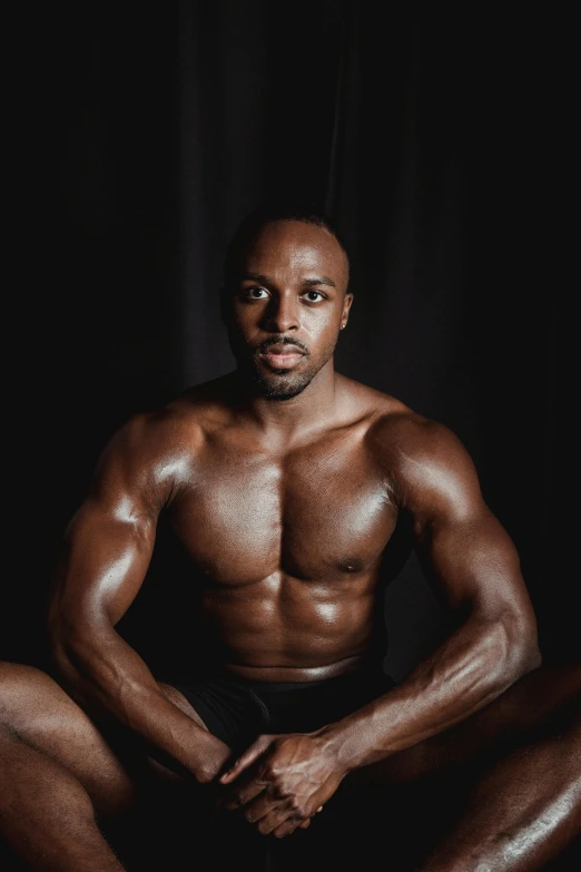 a man that is sitting down in the dark, an album cover, by Jessie Alexandra Dick, pexels contest winner, les nabis, ifbb fitness body, african aaron paul, symmetrical eyes and body, clean background