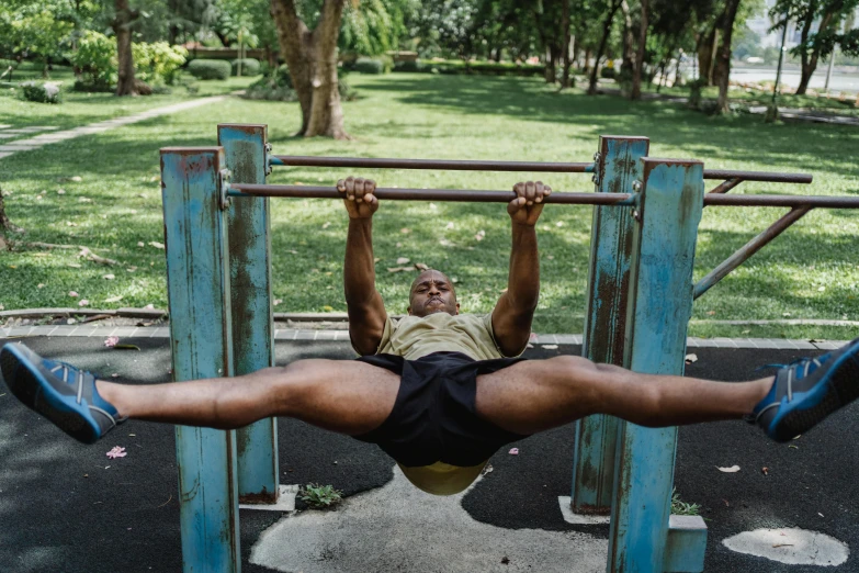 a man on a pull up bar in a park, by Matija Jama, pexels contest winner, hyperrealism, sri lanka, lying down, bulging muscles, his legs spread apart