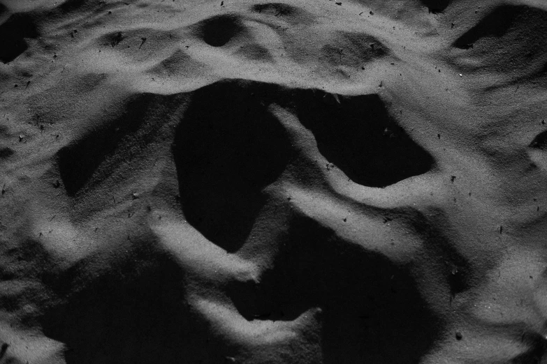 a black and white photo of a face in the snow, an album cover, by Lucio Fontana, conceptual art, full moon buried in sand, nasa footage, abstract claymation, sand banks