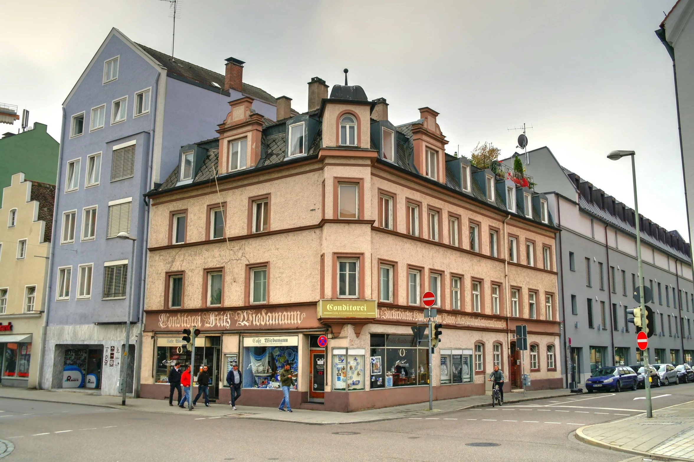 a group of people walking down a street next to tall buildings, a photo, art nouveau, detmold, pink marble building, bookshops, photo for a store