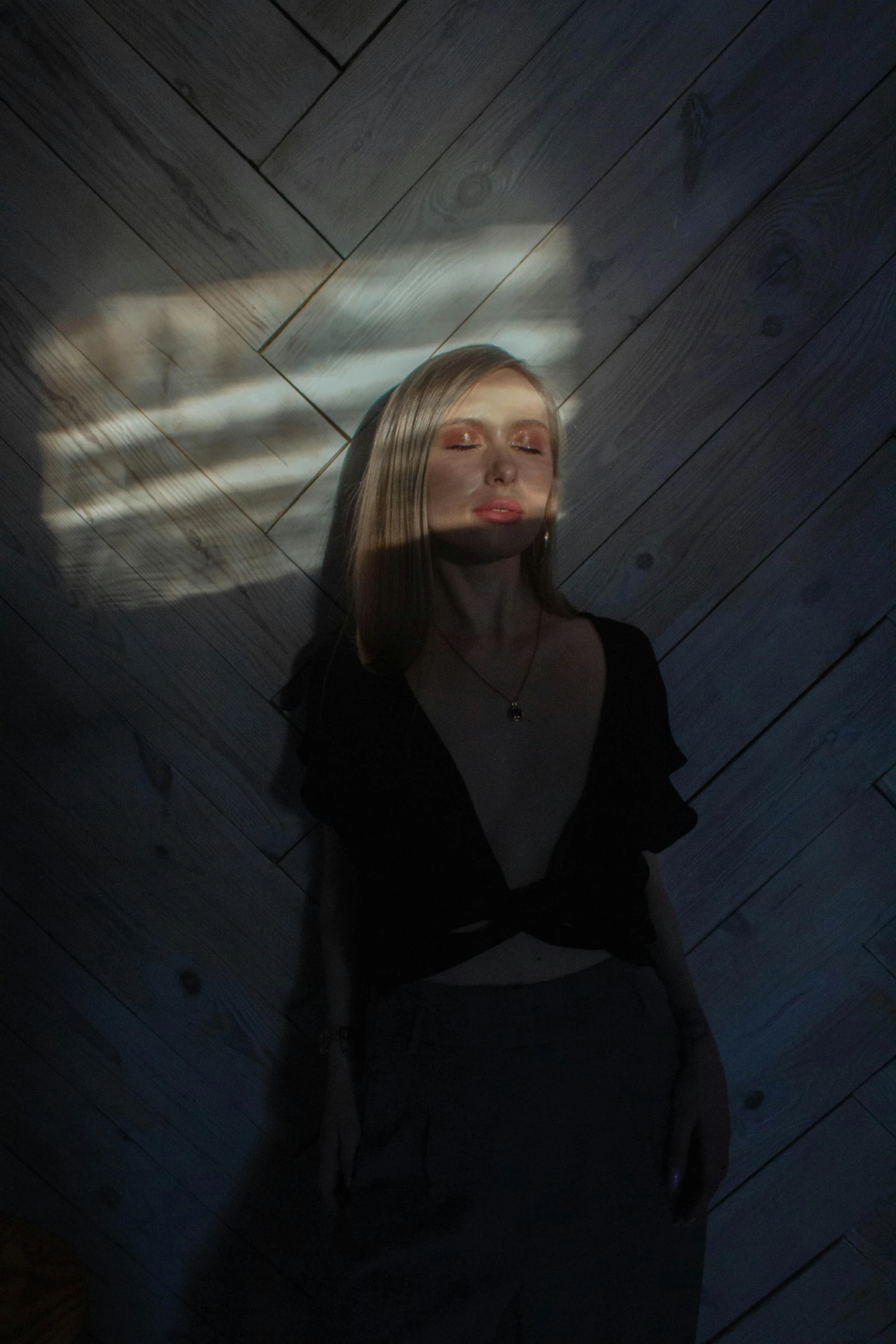 a woman standing in a dimly lit room, inspired by Elsa Bleda, aestheticism, a blond, god ray across her face, erin moriarty, petra collins and mc. escher