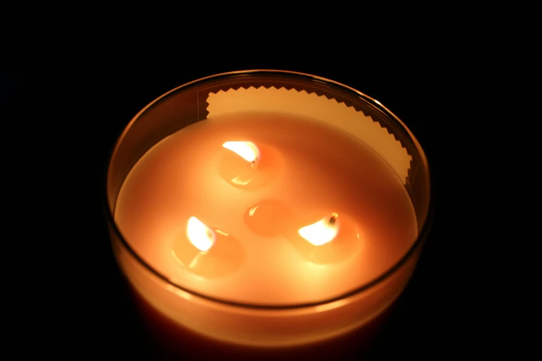 a close up of a lit candle in a glass, inspired by Carrie Mae Weems, glowing buttons, top - down view, centred, relaxing