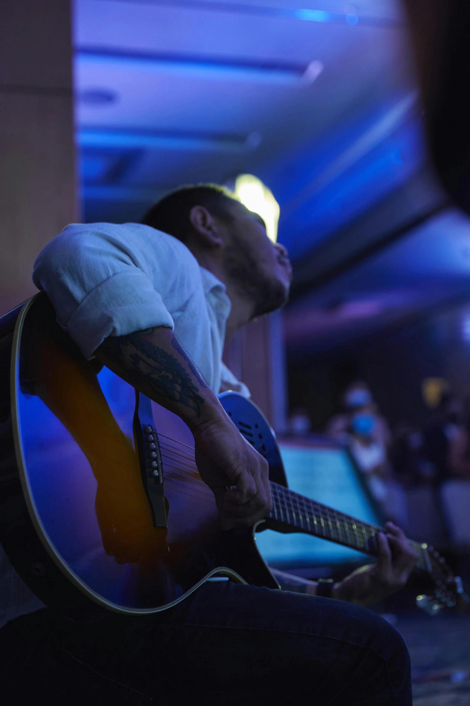 a man that is sitting down with a guitar, happening, dramatic white and blue lighting, slide show, profile image, dj at a party