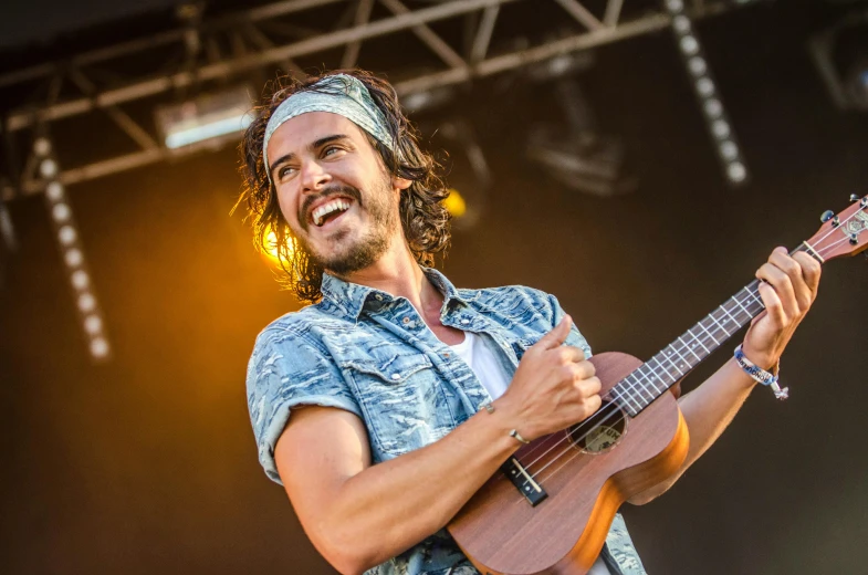 a man holding a guitar on top of a stage, by Jacob Toorenvliet, with hawaiian shirt, smug grin, arrendajo in avila pinewood, avatar image