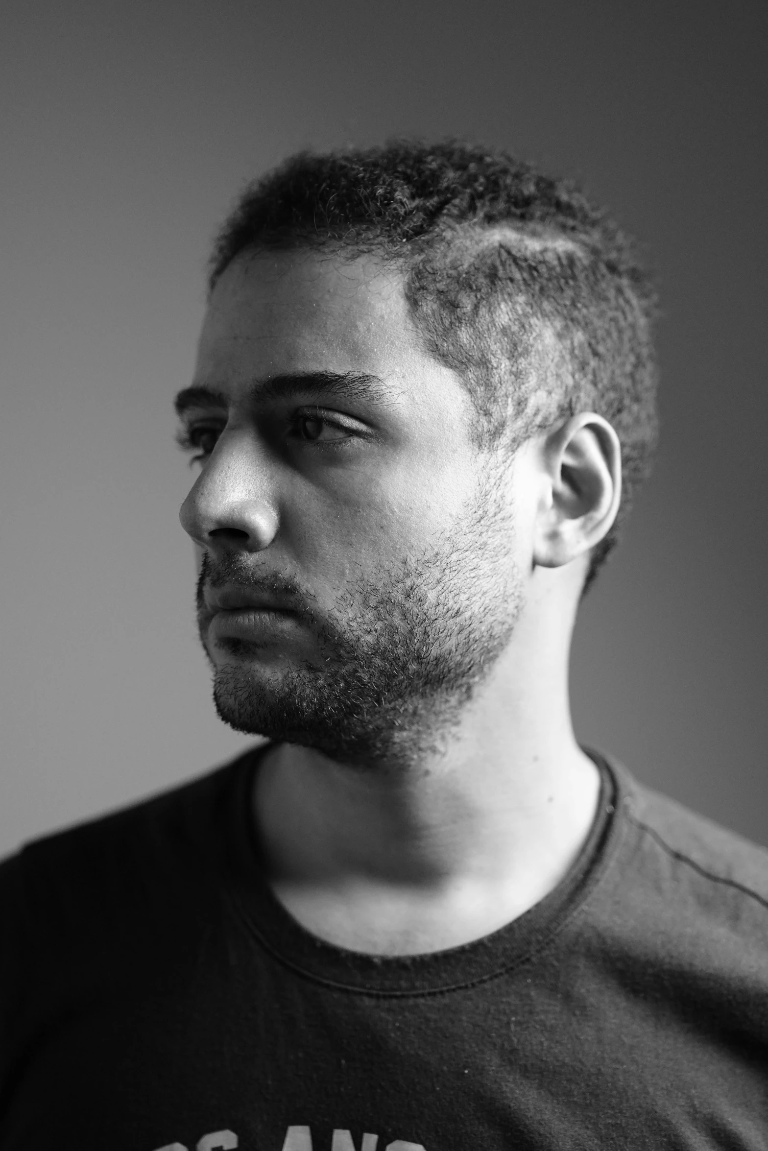 a black and white photo of a man in a t - shirt, a character portrait, inspired by Ahmed Yacoubi, aida muluneh, scruffy looking, brazilian ronaldo, post malone