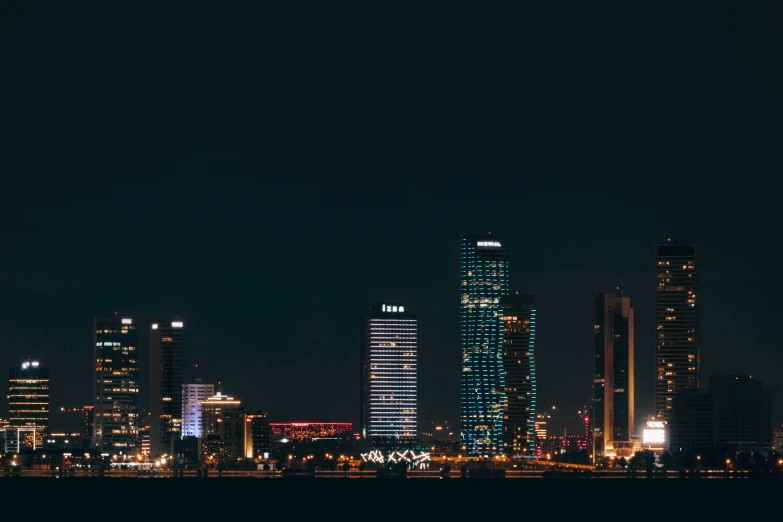 a view of a city at night from the water, pexels contest winner, minimalism, capital of estonia, karachi skyline background, gif, group photo