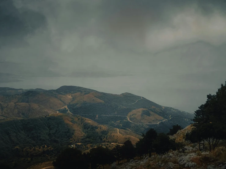 a person standing on top of a hill under a cloudy sky, a matte painting, by Elsa Bleda, unsplash contest winner, mulholland drive, view from slightly above, gloomy weather. hyperrealistic, italy