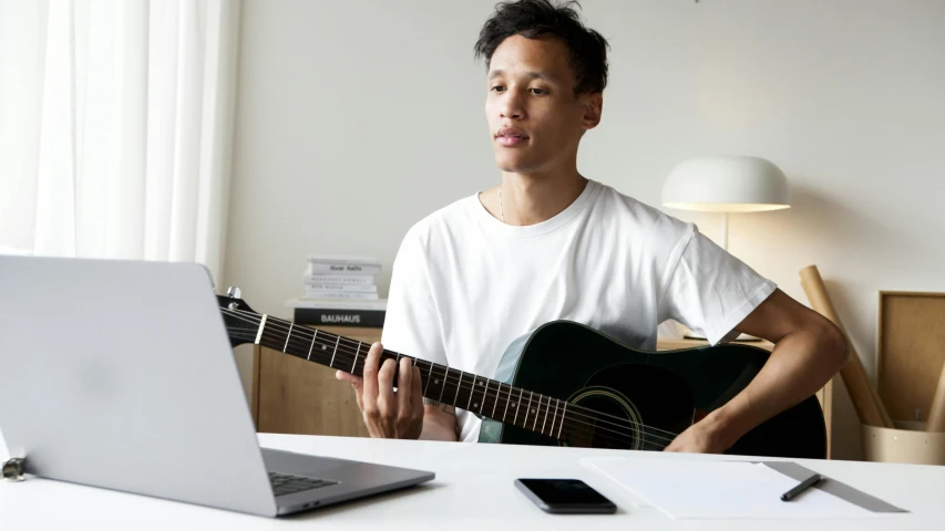 a man playing a guitar in front of a laptop, inspired by Simon Gaon, pexels contest winner, looking across the shoulder, sydney park, no - text no - logo, portrait of tall