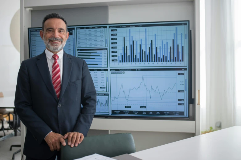 a man in a suit standing in front of a monitor, by Alejandro Obregón, graphs, portrait photo, 15081959 21121991 01012000 4k, pablo amaringo