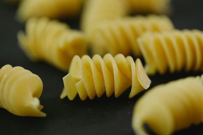 a pile of pasta sitting on top of a table, a macro photograph, trending on pexels, larvae, butter, ilustration, cuts