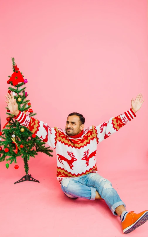 a man sitting in front of a christmas tree, an album cover, pexels, hurufiyya, shrugging arms, indian, adult man, gif