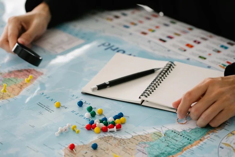 a person sitting at a table with a notebook and pen, a child's drawing, pexels contest winner, dices map book miniatures, nautical maps, thumbnail, national geograpic