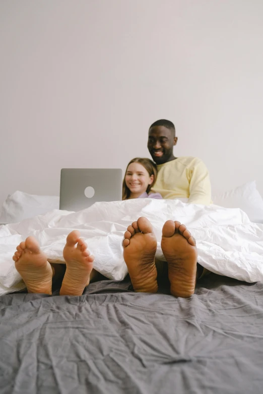 a man and a woman sitting on top of a bed, by Carey Morris, pexels contest winner, programming, big feet, diverse, laptops