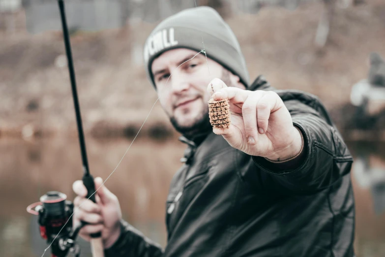 a man holding a fishing rod next to a lake, a photo, by Mathias Kollros, pexels contest winner, hurufiyya, gills and scales, holding a small vape, micro detailed, brown