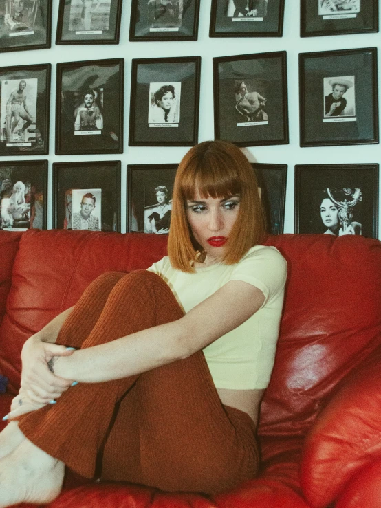 a woman sitting on top of a red couch, an album cover, inspired by Nan Goldin, trending on pexels, better known as amouranth, brown bangs, cinematic outfit photo, piercing stare