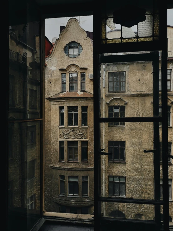 a view of a building through a window, inspired by Lajos Gulácsy, pexels contest winner, art nouveau, black windows, panorama view, dark and beige atmosphere, a high angle shot