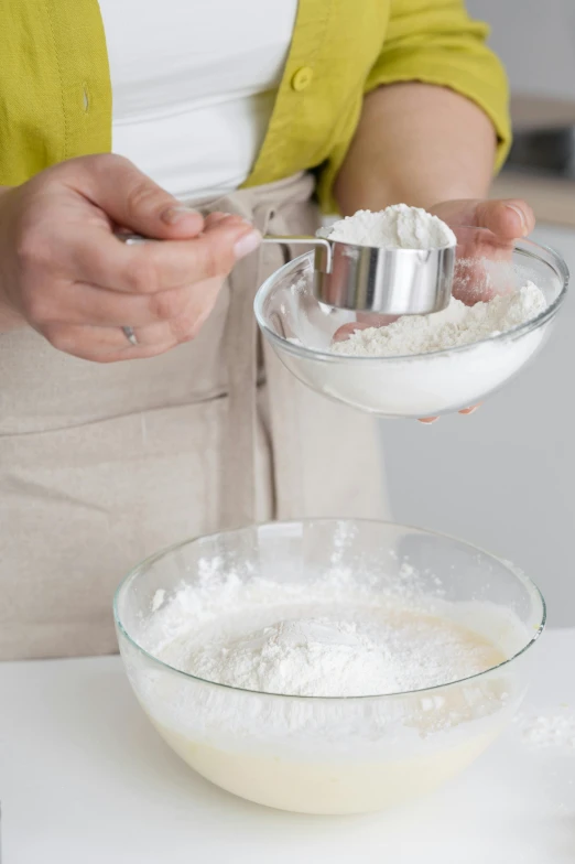 a woman mixing ingredients in a bowl on a counter, by Lucette Barker, covered in white flour, detailed product image, detail shot, stainless steel