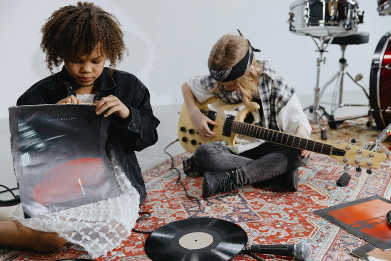 a group of people sitting on top of a floor, an album cover, by Emma Andijewska, pexels contest winner, kids playing, playing electric guitar, in plastic, boombox