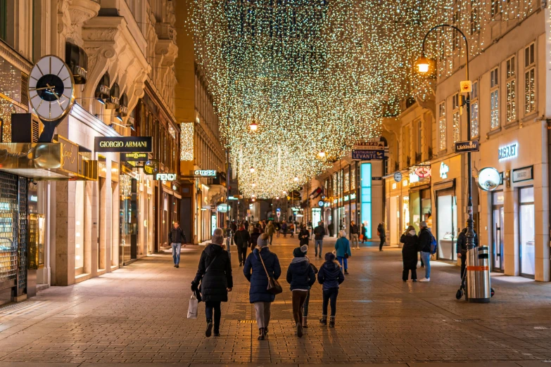 a group of people walking down a city street, a photo, by Julia Pishtar, shutterstock, hyperrealism, christmas lights, hungarian, lights on ceiling, sparsely populated