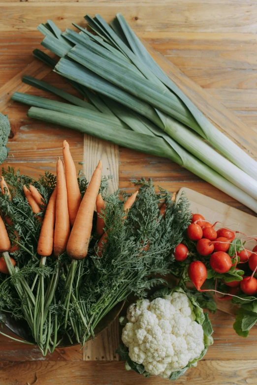 a bunch of vegetables sitting on top of a wooden table, lush greens, carrots, bay area, soft glow