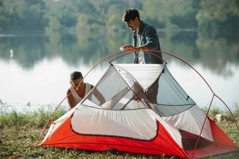 two people setting up a tent next to a lake, red and white color theme, fan favorite, product introduction photo, high elevation