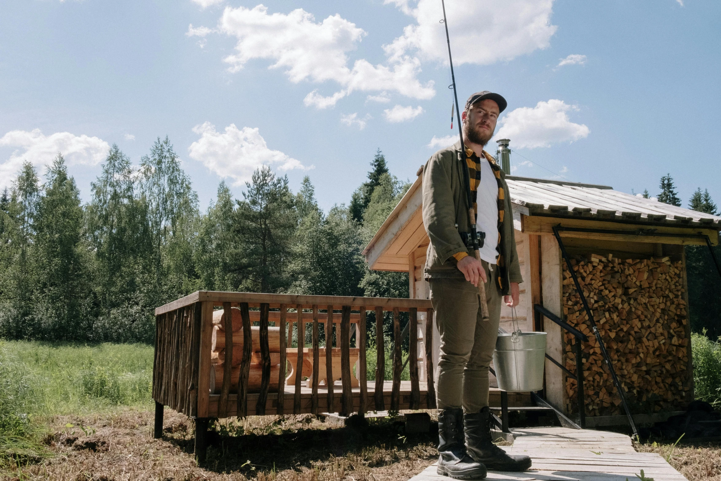 a man standing on top of a wooden platform, a picture, by Anato Finnstark, trout in pants, glamping, wearing a fisher 🧥, high quality upload