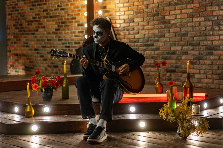 a man that is sitting down with a guitar, by Julia Pishtar, pexels contest winner, vanitas, in a halloween style, indoor setting, profile image, full face shot